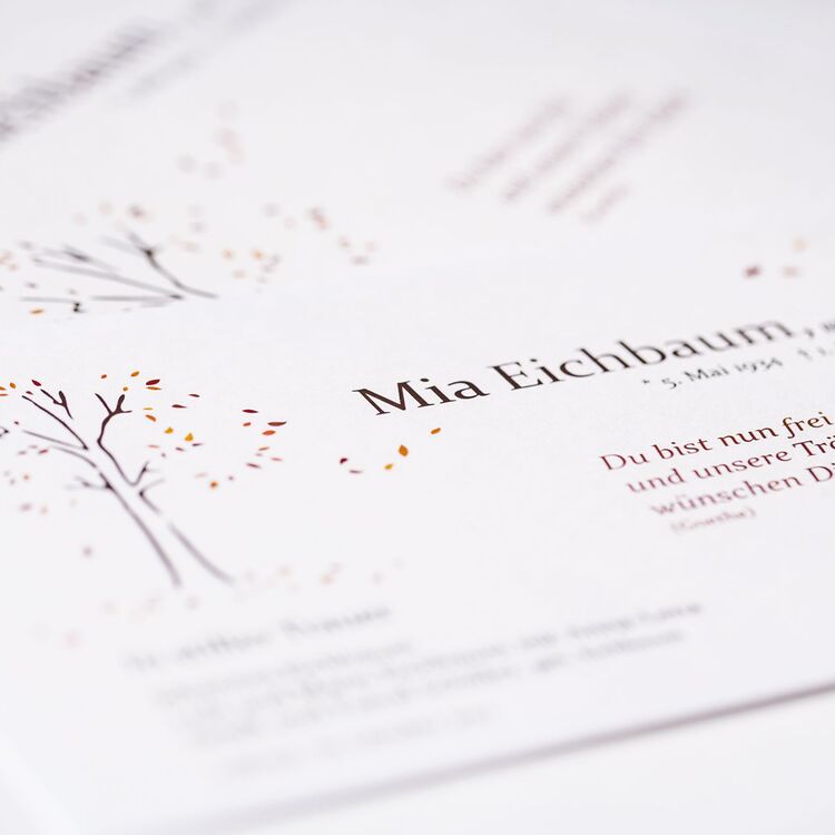 Eine Einladungskarte zu einer Trauerfeier. Auf der Karte steht der Name der Person sowie das Todesdatum. Ein skizzierter Baum befindet sich links auf der Karte.