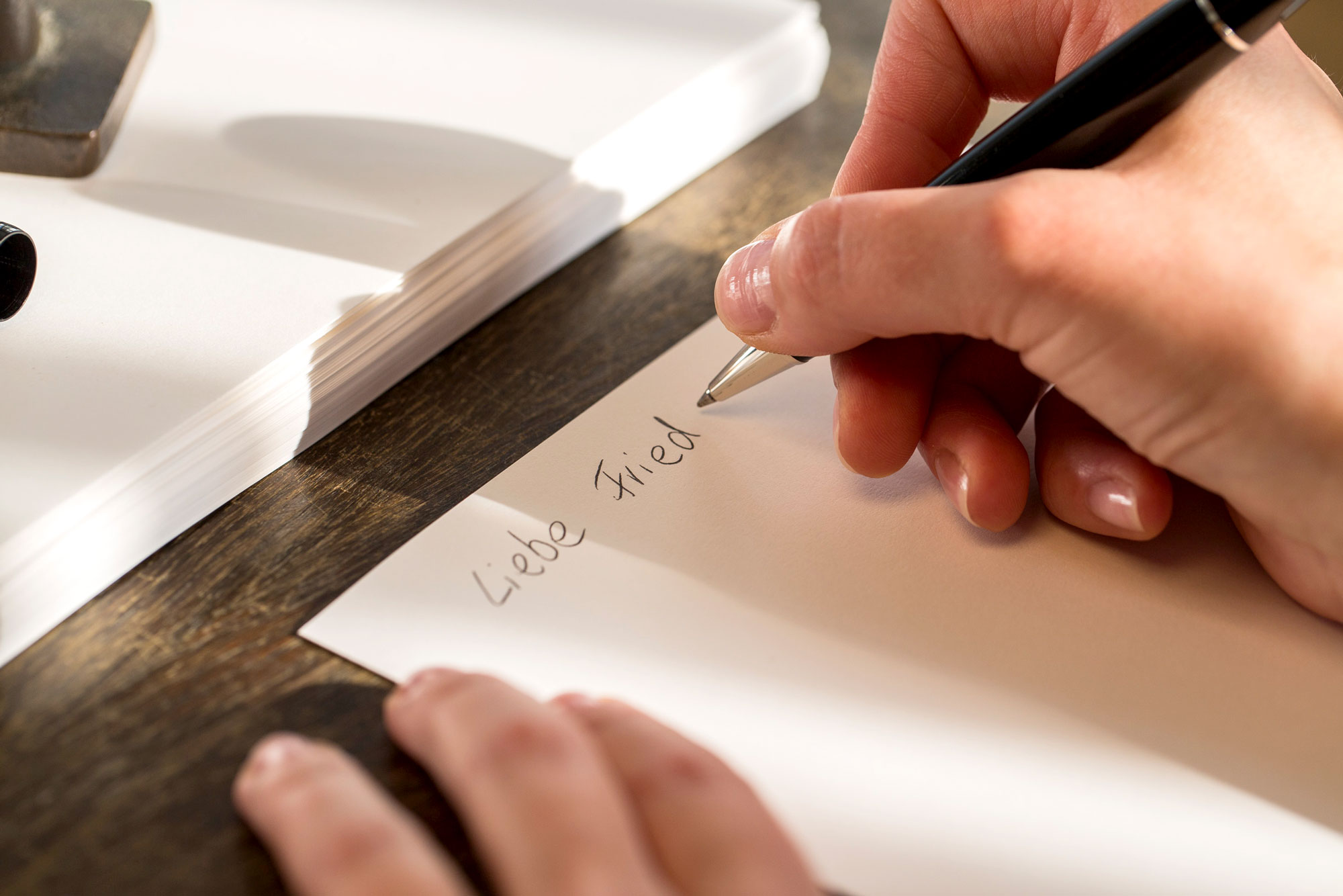 Eine Person schreibt einen Brief an einen Hinterbliebenen, um zu kondolieren.