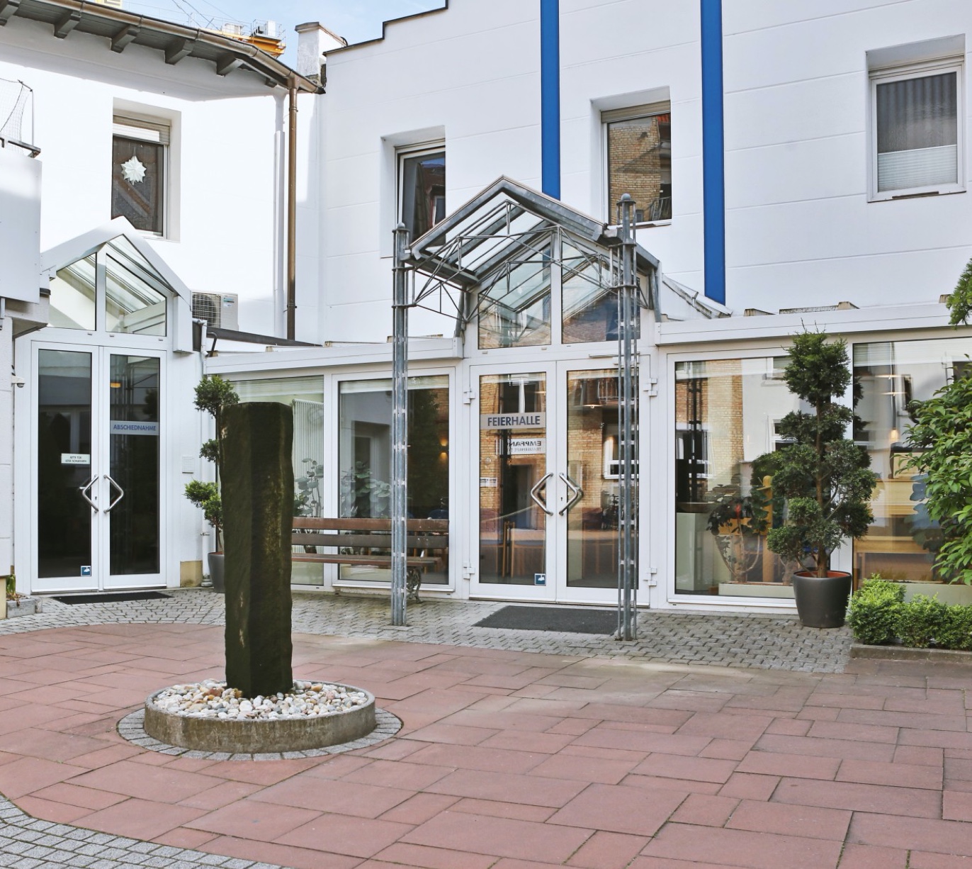 Innenhof der Trauerhilfe Stier in Karlsruhe. Gläserner Eingang, mittig ein Brunnen.