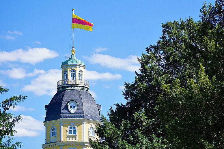 Der Turm vom Schloss in Karlsruhe mit einer Flagge auf der Spitze.