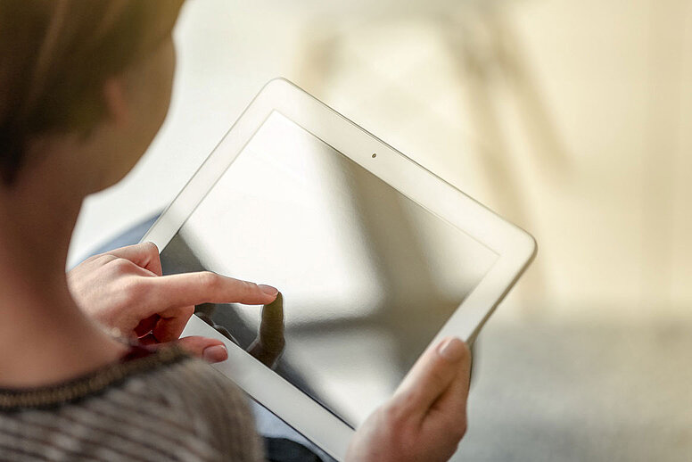 Eine Person hält ein Tablet in beiden Händen.