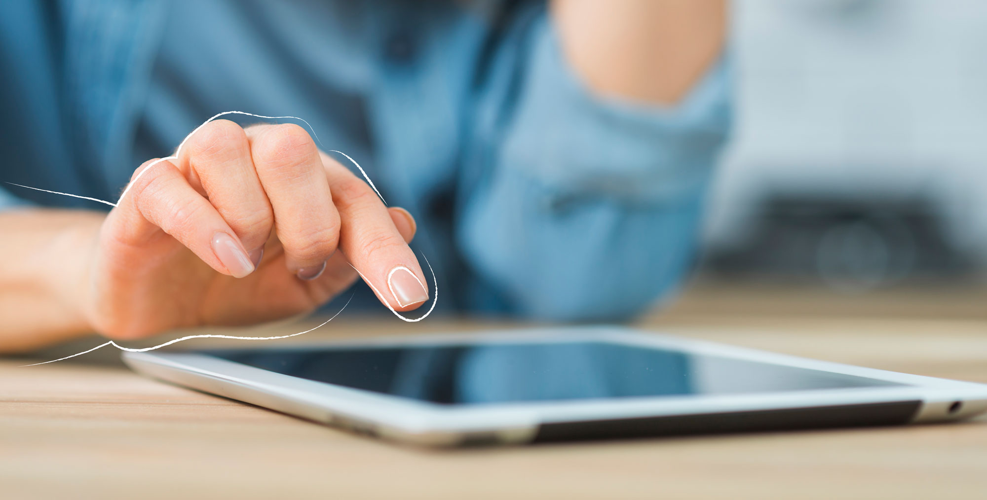 Eine Person in einem blauen Pulli tippt auf einem Tablet.